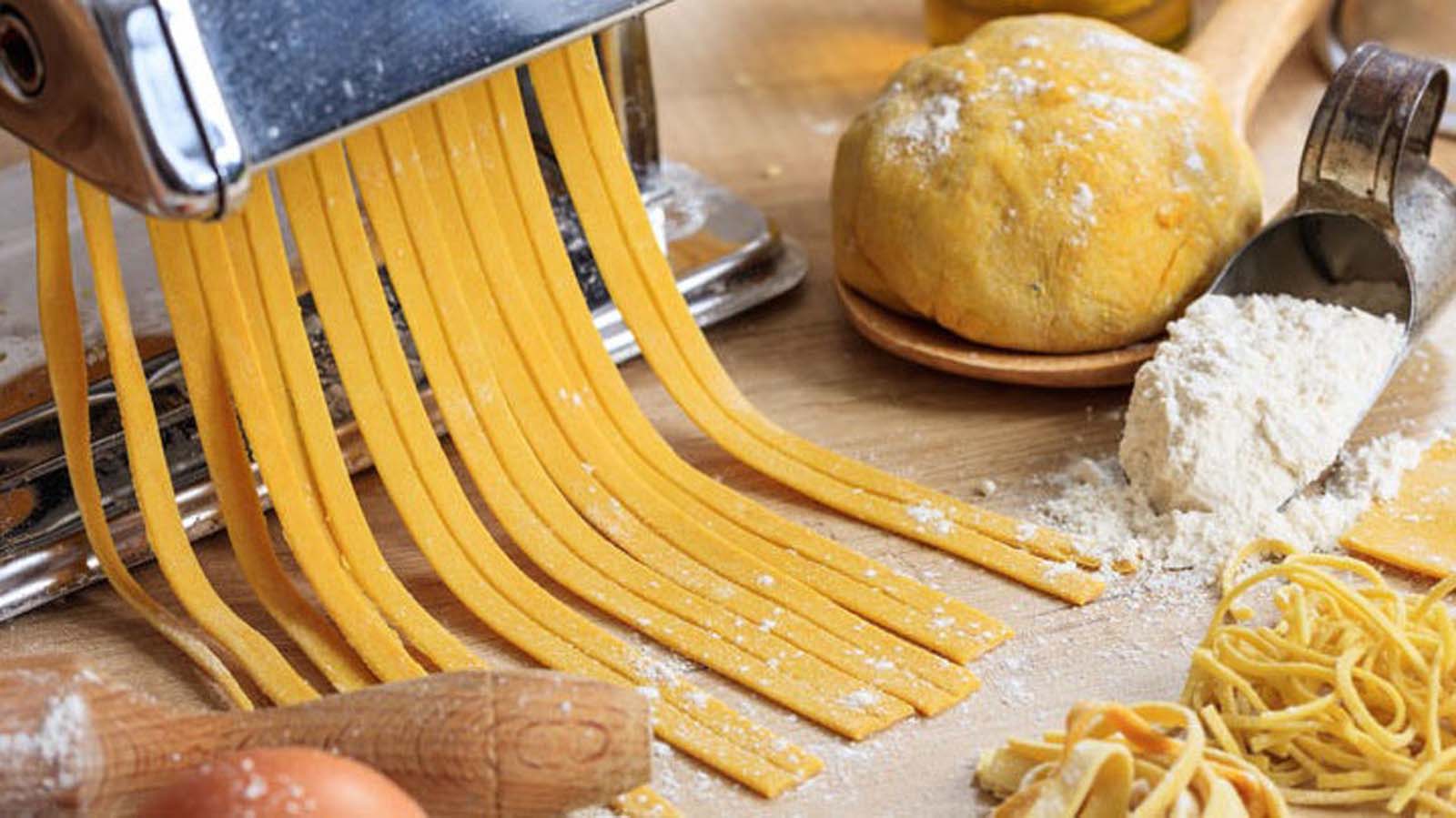 Freshly rolled out smooth yellow basic pasta dough on a floured workbench.