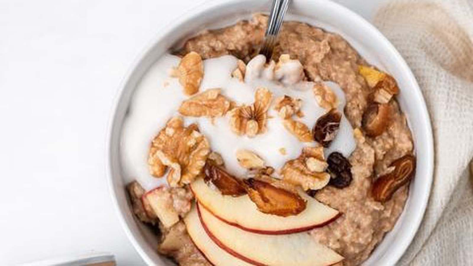 A warm, wholesome breakfast bowl of apple cinnamon oatmeal porridge topped with fruit.
