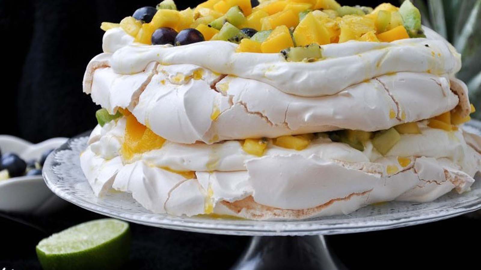 A giant, beautiful Australian pavlova meringue cake loaded with cream and summer berries.