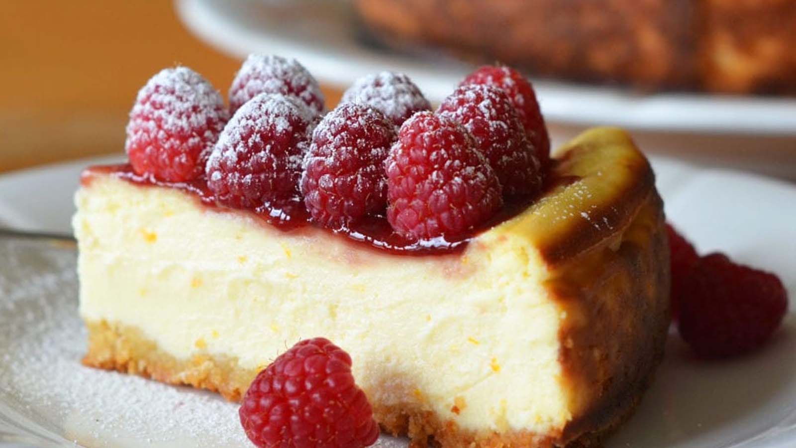 A slice of creamy baked cheesecake with a golden crumb crust on a dessert plate.