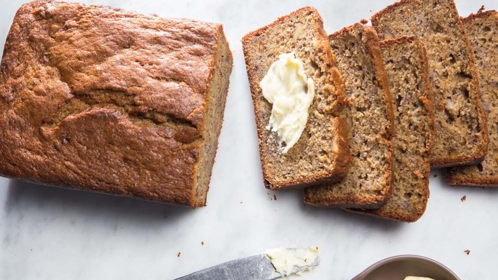 Moist homemade banana loaf sliced neatly on a cooling rack.