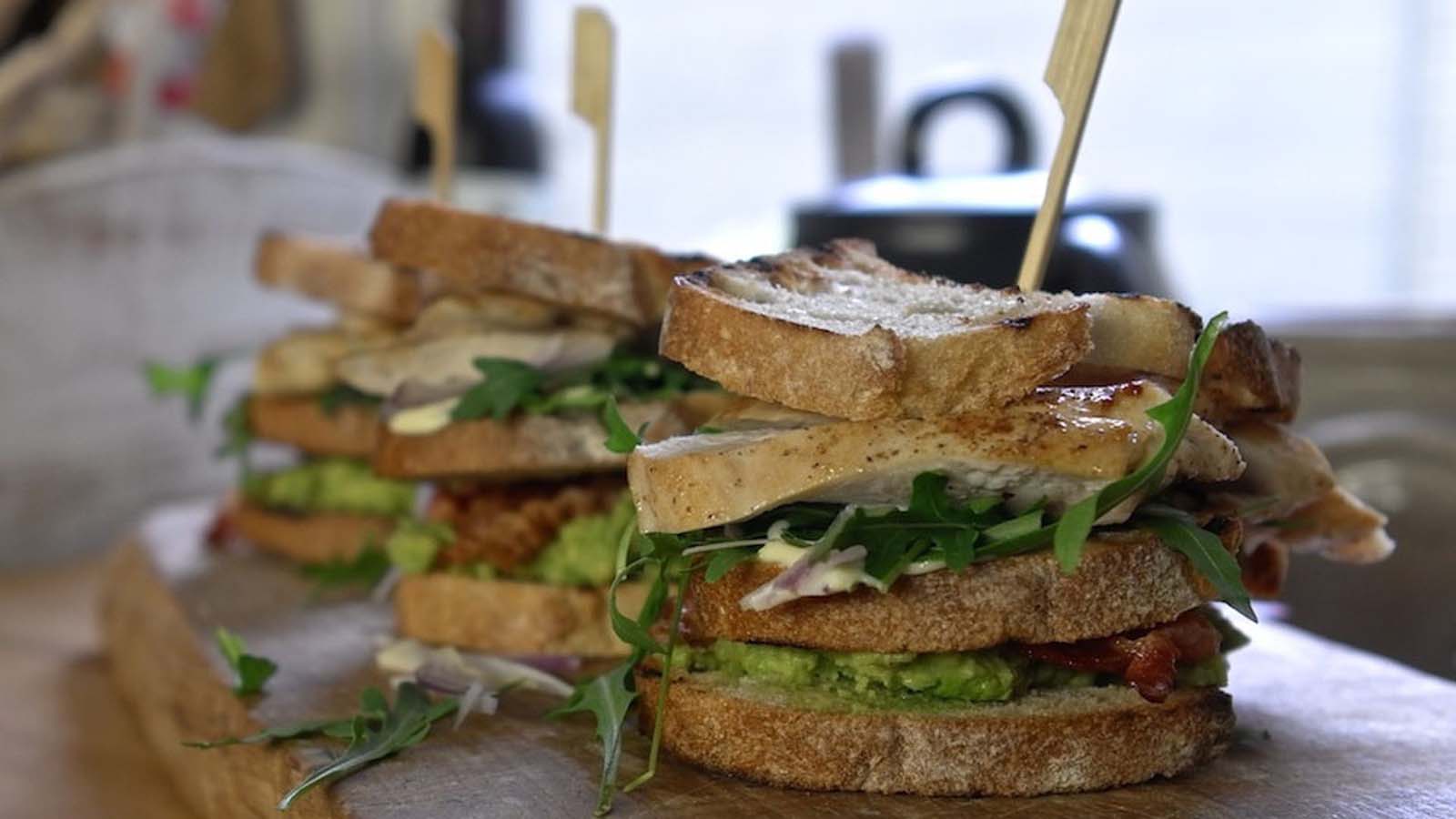 A layered BBQ chicken club sandwich sliced diagonally into neat triangles.