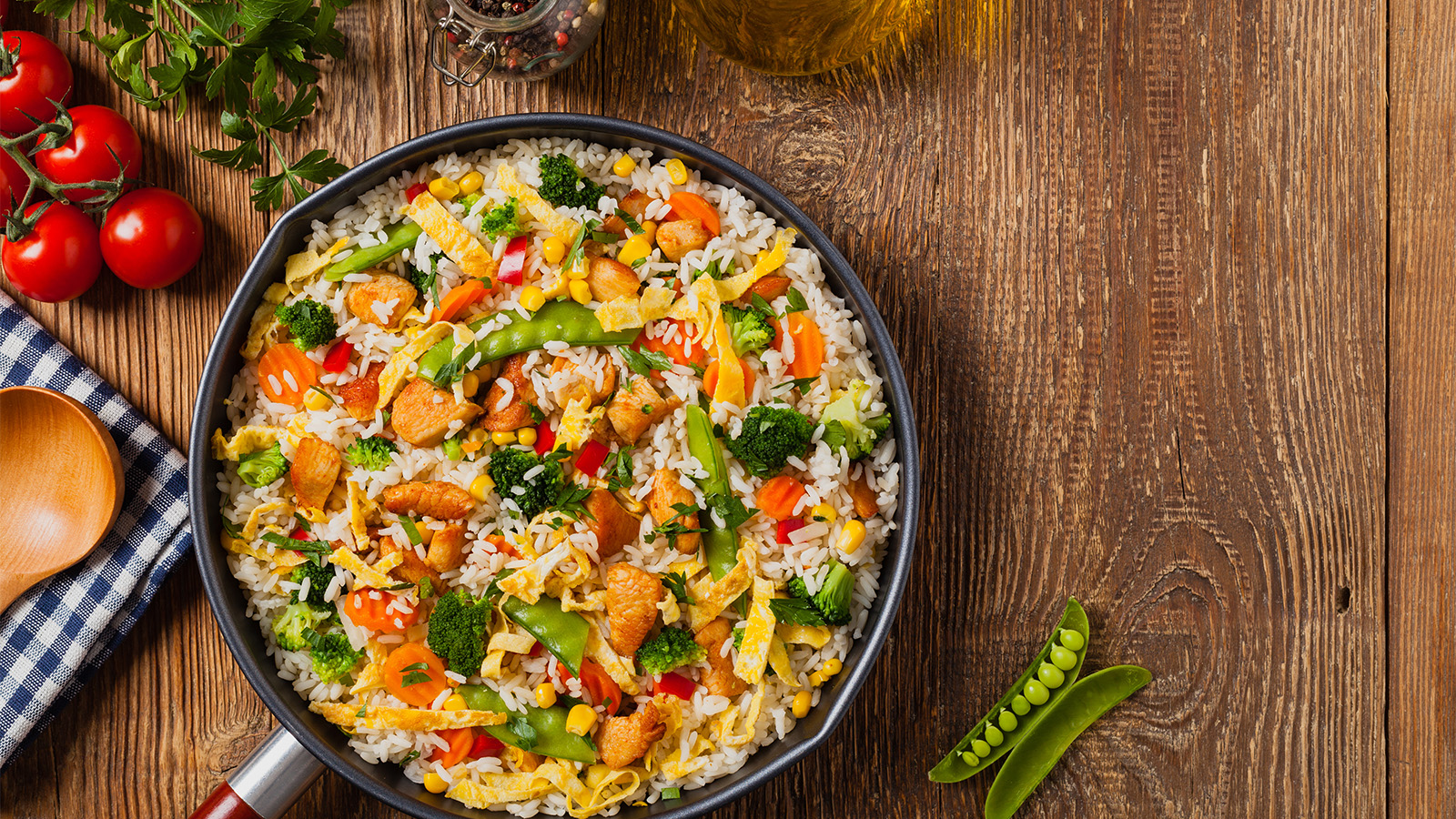 A hot wok filled with savoury chicken egg fried rice tossed with green peas.