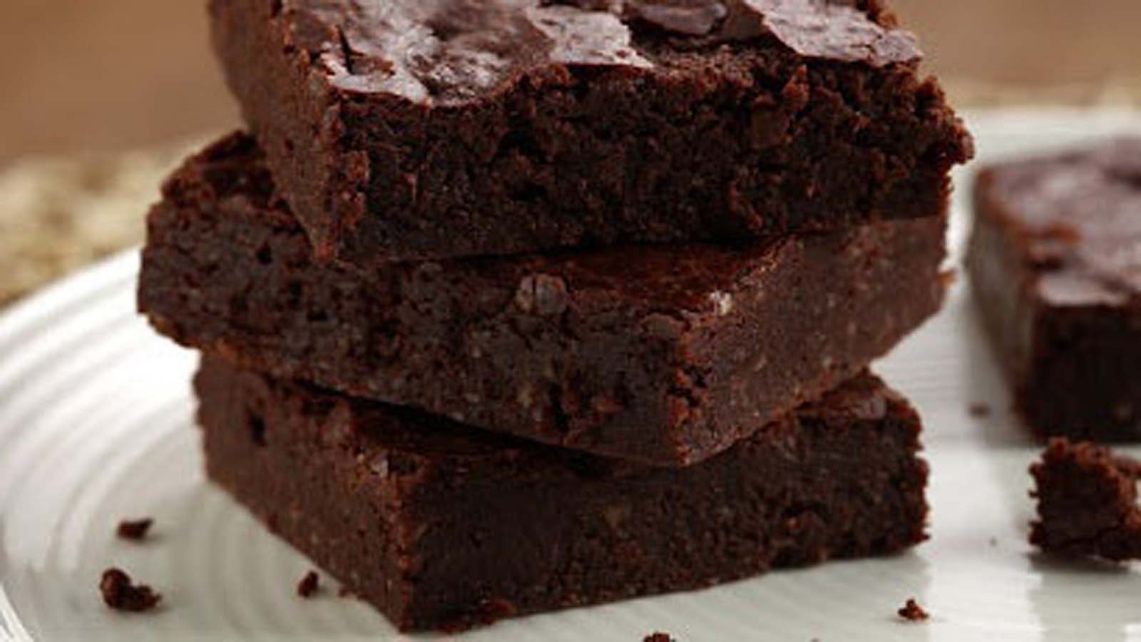 Fudgy and dense chocolate brownies sliced into thick squares on a wire rack.