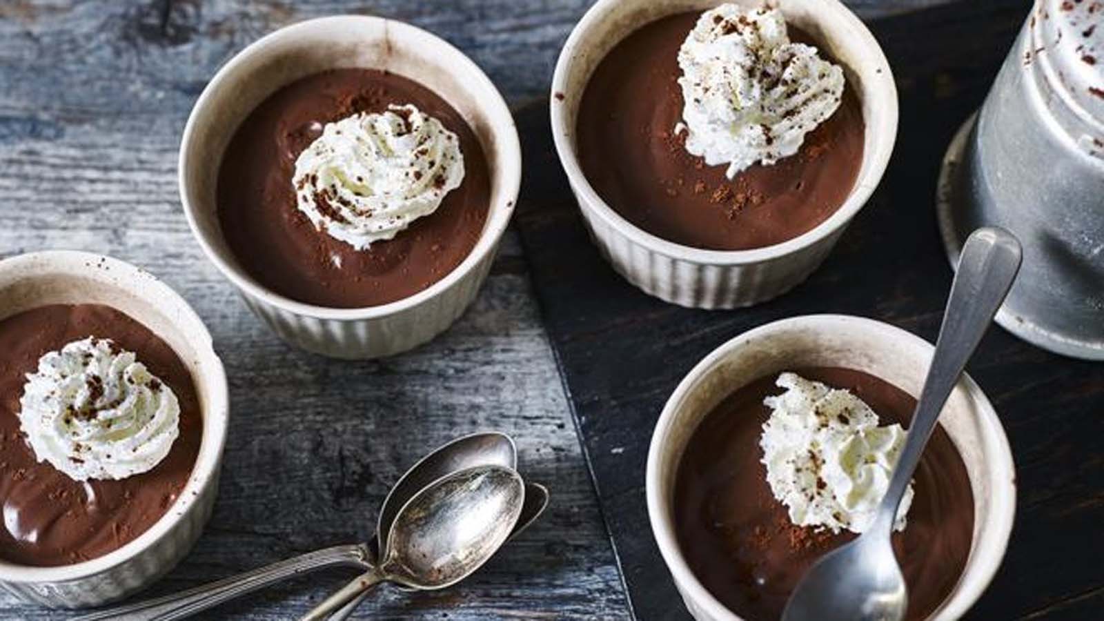 Individual rich chocolate pots de creme desserts chilled in ceramic ramekins.