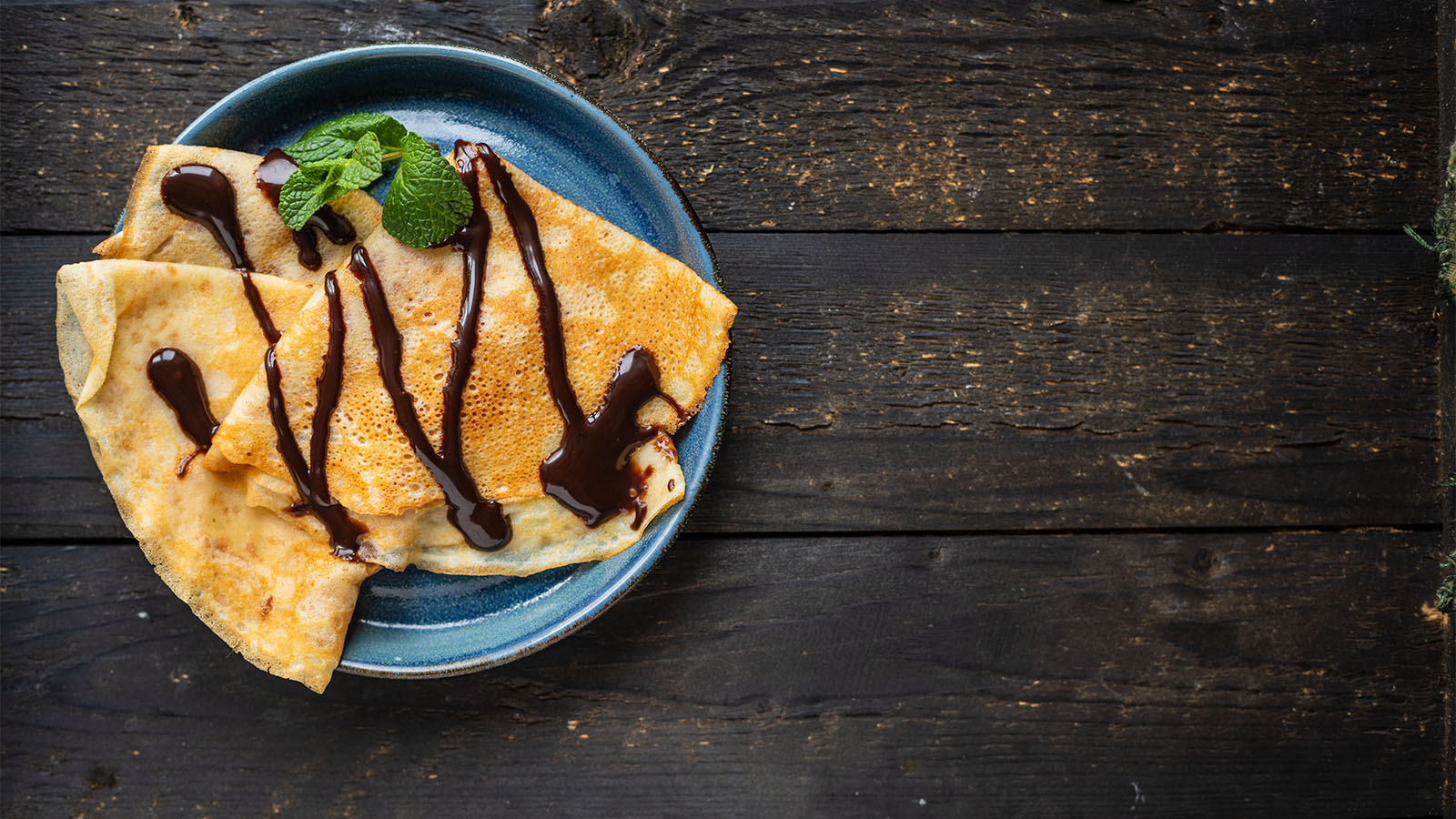 A decadent rich dark chocolate sauce pouring smoothly onto a dessert bowl.