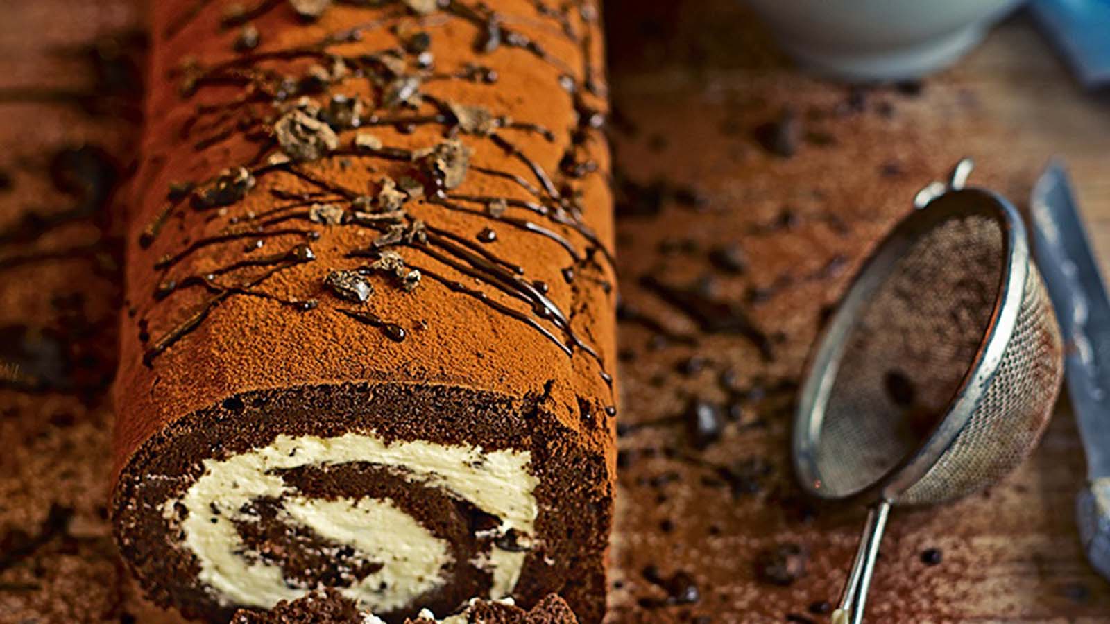 A beautiful chocolate swiss roll cake swirled cleanly with white cream filling.