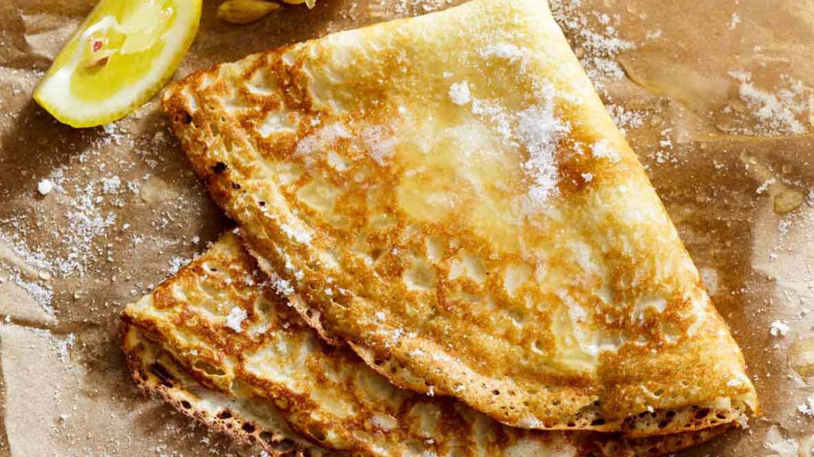 A tall stack of thin, golden brown French crepe pancakes ready for sweet toppings.