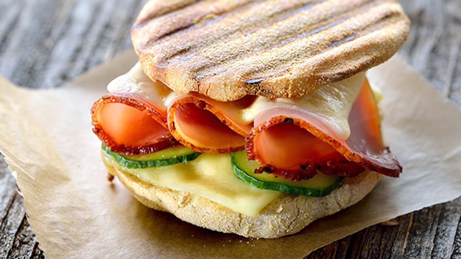 A perfectly toasted Italian panini sandwich filled with melting cheese, tomato, and ham.