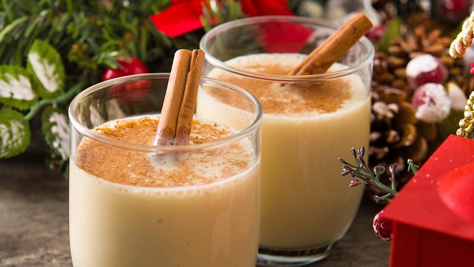 A festive glass cup filled with thick, creamy holiday eggnog sprinkled with nutmeg powder.