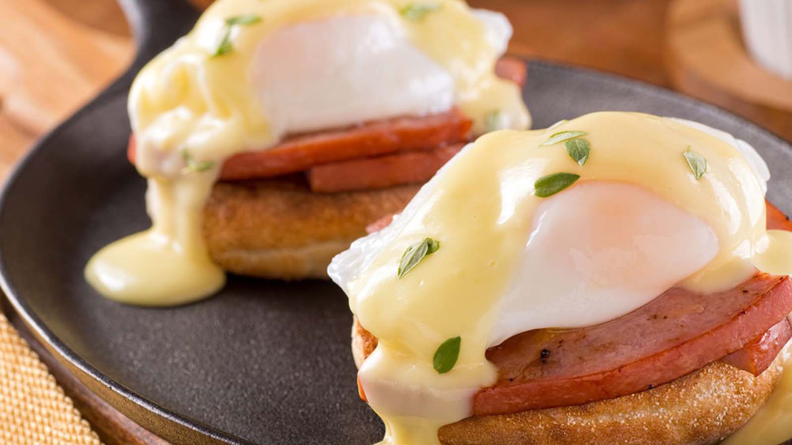Classic eggs benedict with poached eggs and ham over toasted English muffins.