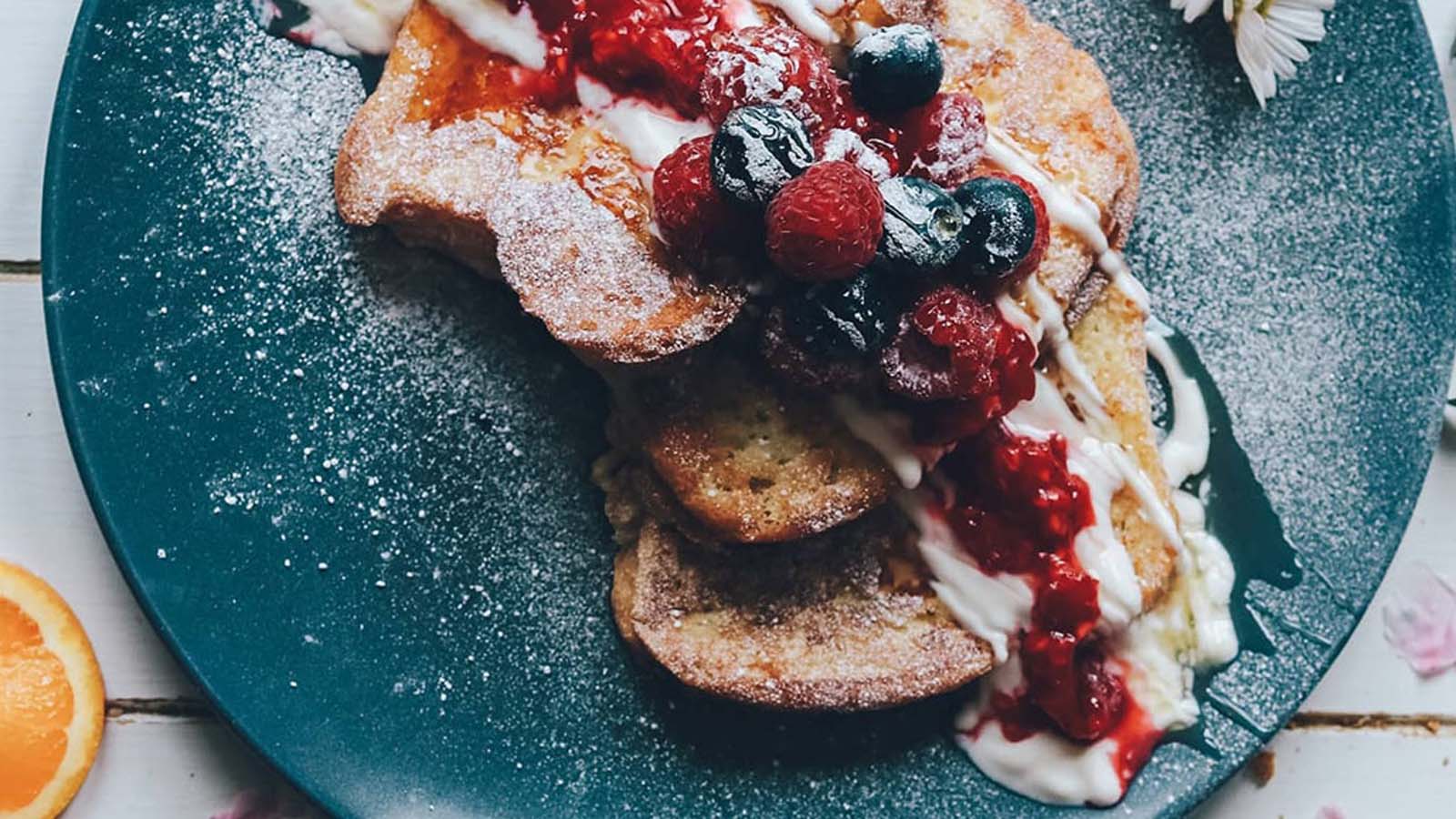 Healthy French toast topped with thick creamy yogurt, mixed wild berries, and honey drizzle.