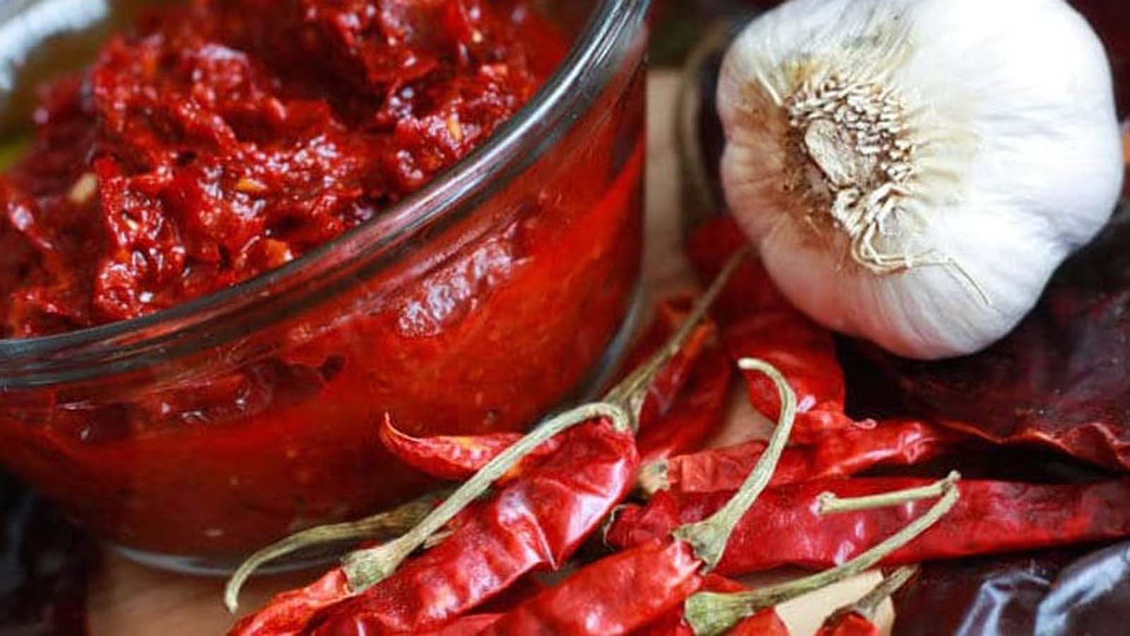 A deep red, fiery North African harissa paste chili sauce mix inside a jar.