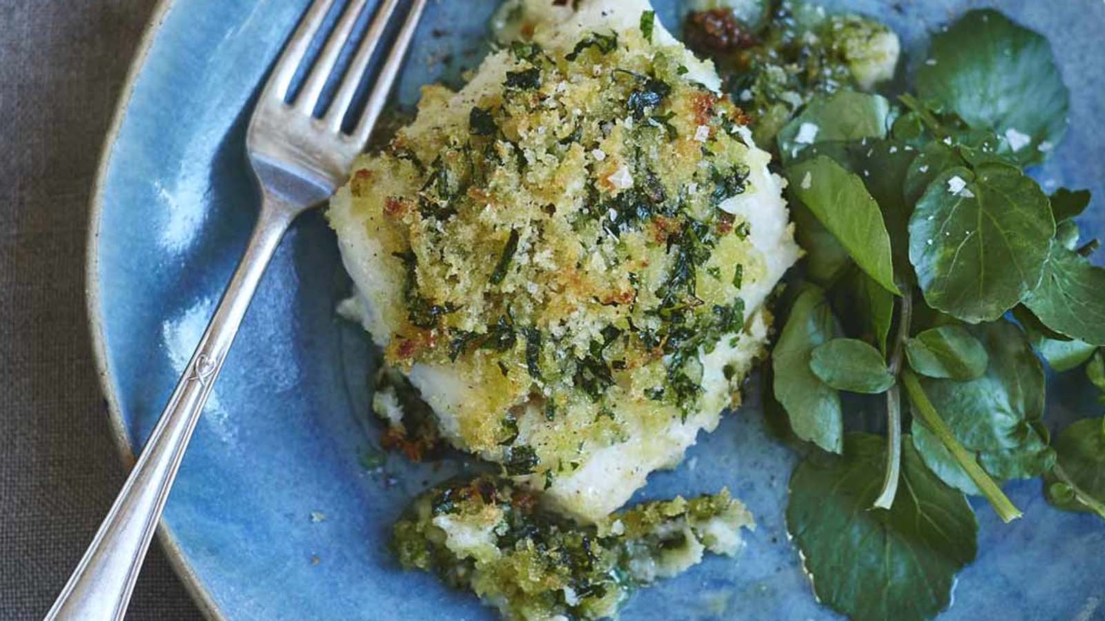 A fresh green herb crust mix pressed onto a white fish fillet for baking.