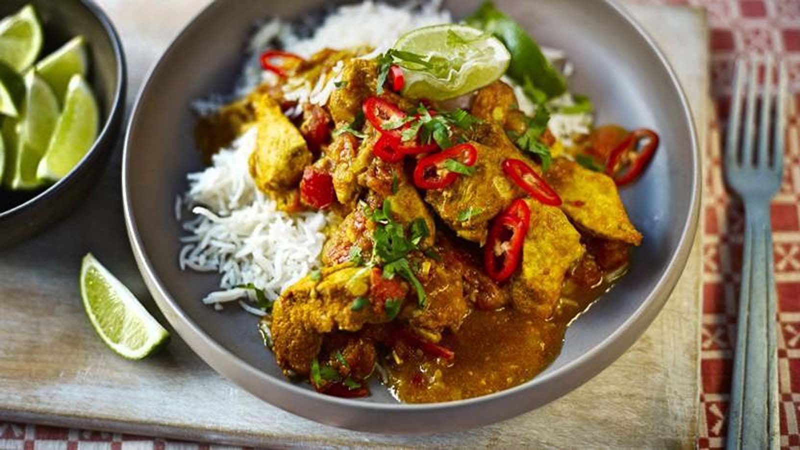 An aromatic Indian chicken curry served alongside a bed of bright yellow saffron rice.