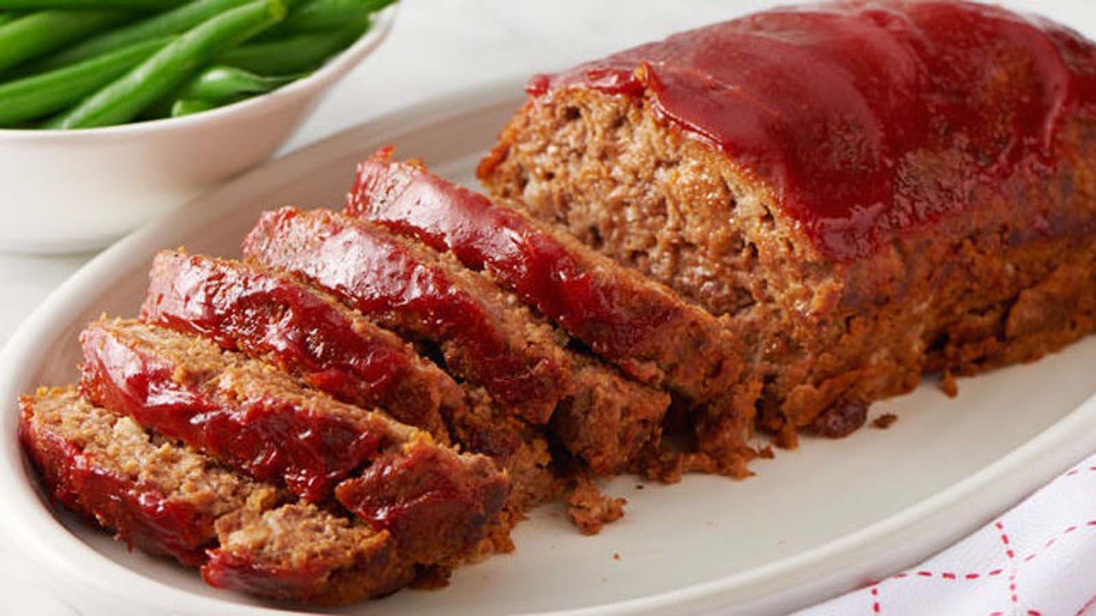 A hearty, dense homemade savoury baked meatloaf sliced clean on a serving platter.