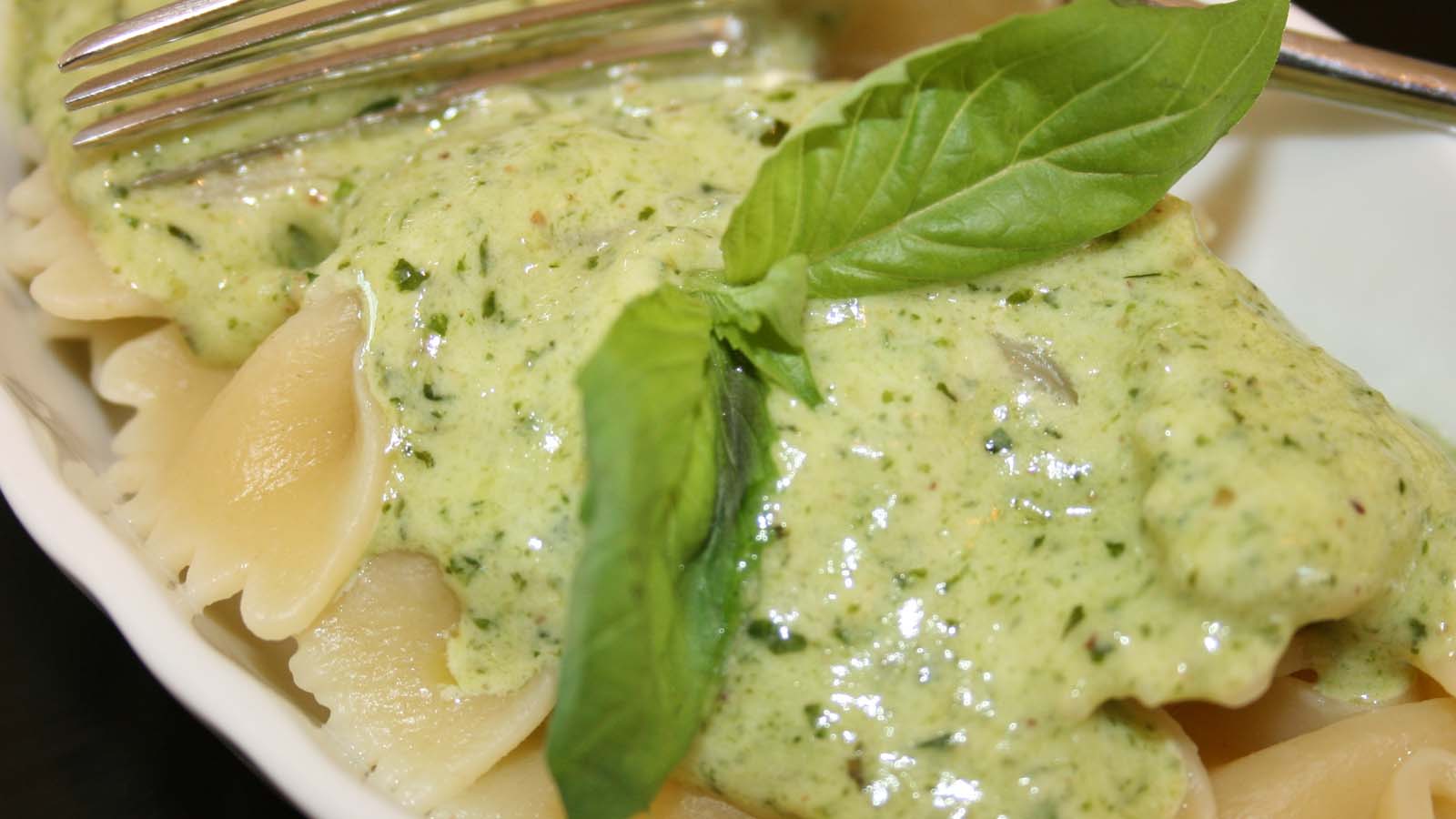 A creamy green pesto pasta sauce blending fresh basil, garlic, and cream.