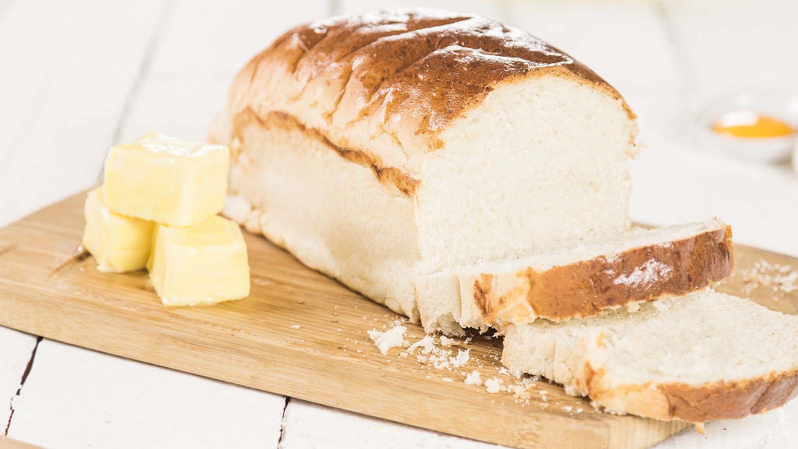 A golden loaf of sliced plain white homemade bread fresh from the oven.