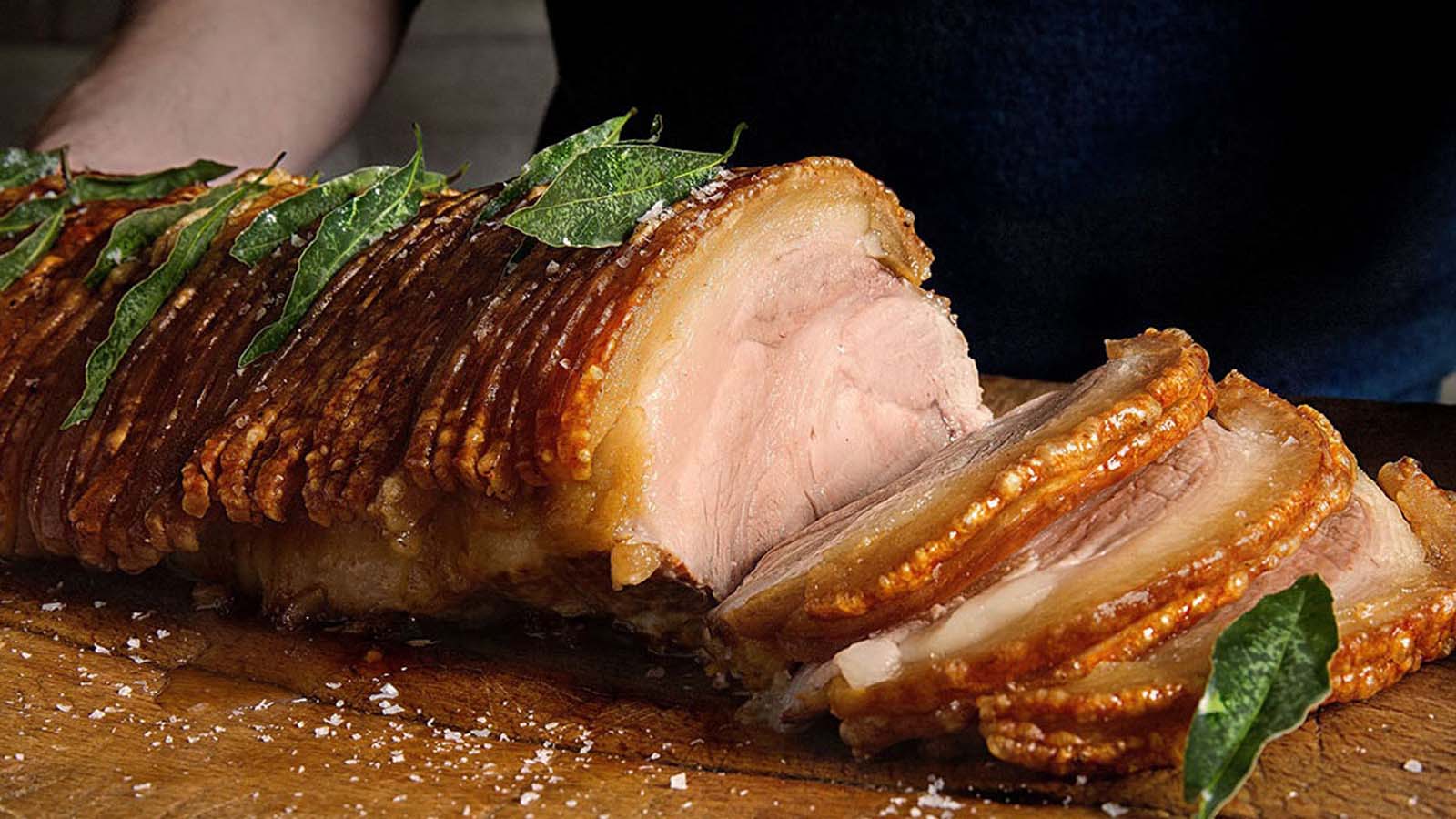 A succulent cut of roast pork roast showing perfect crispy crackling skin on top.