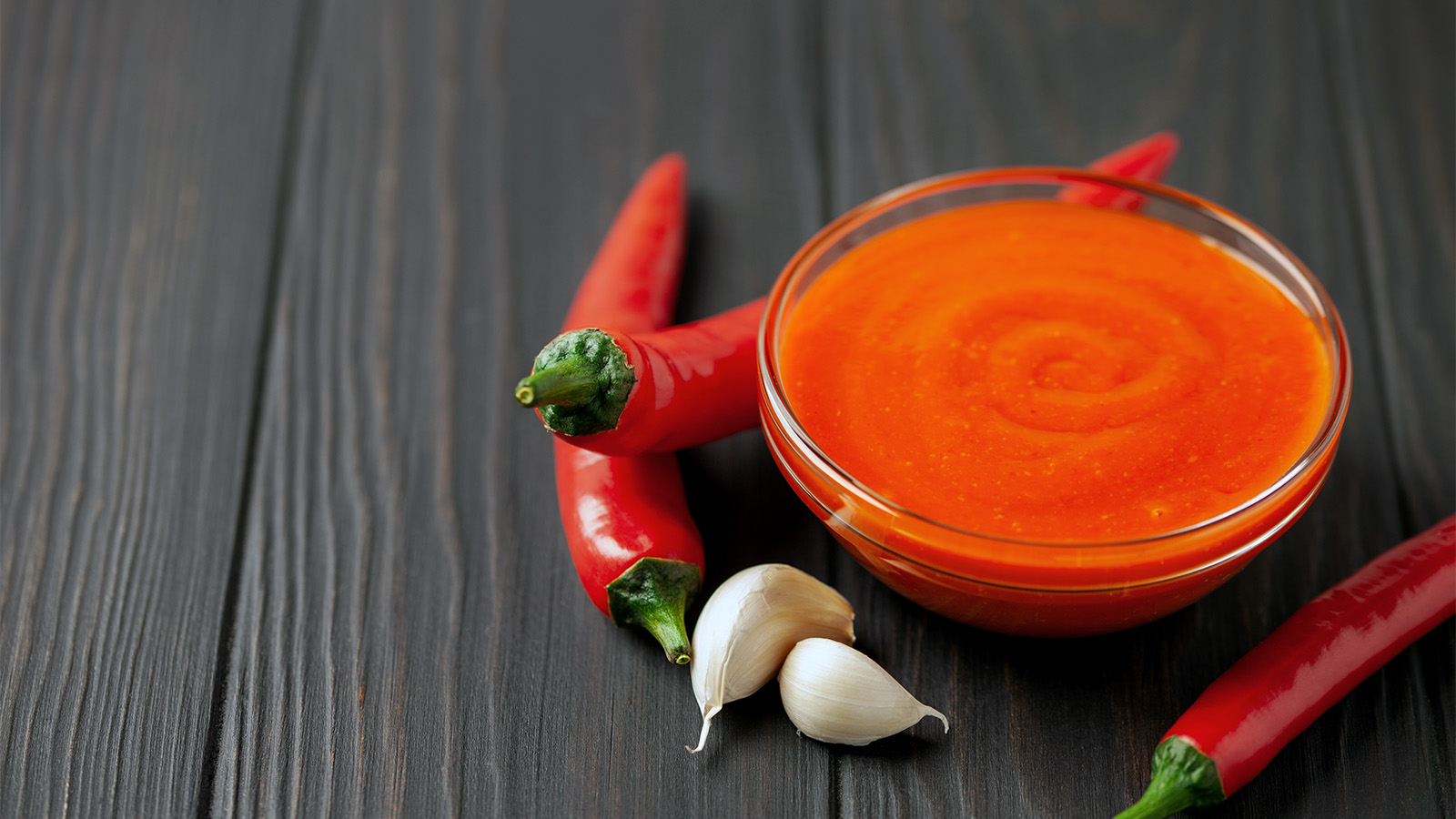 A smooth and vibrant red blended roasted red pepper sauce inside a serving bowl.