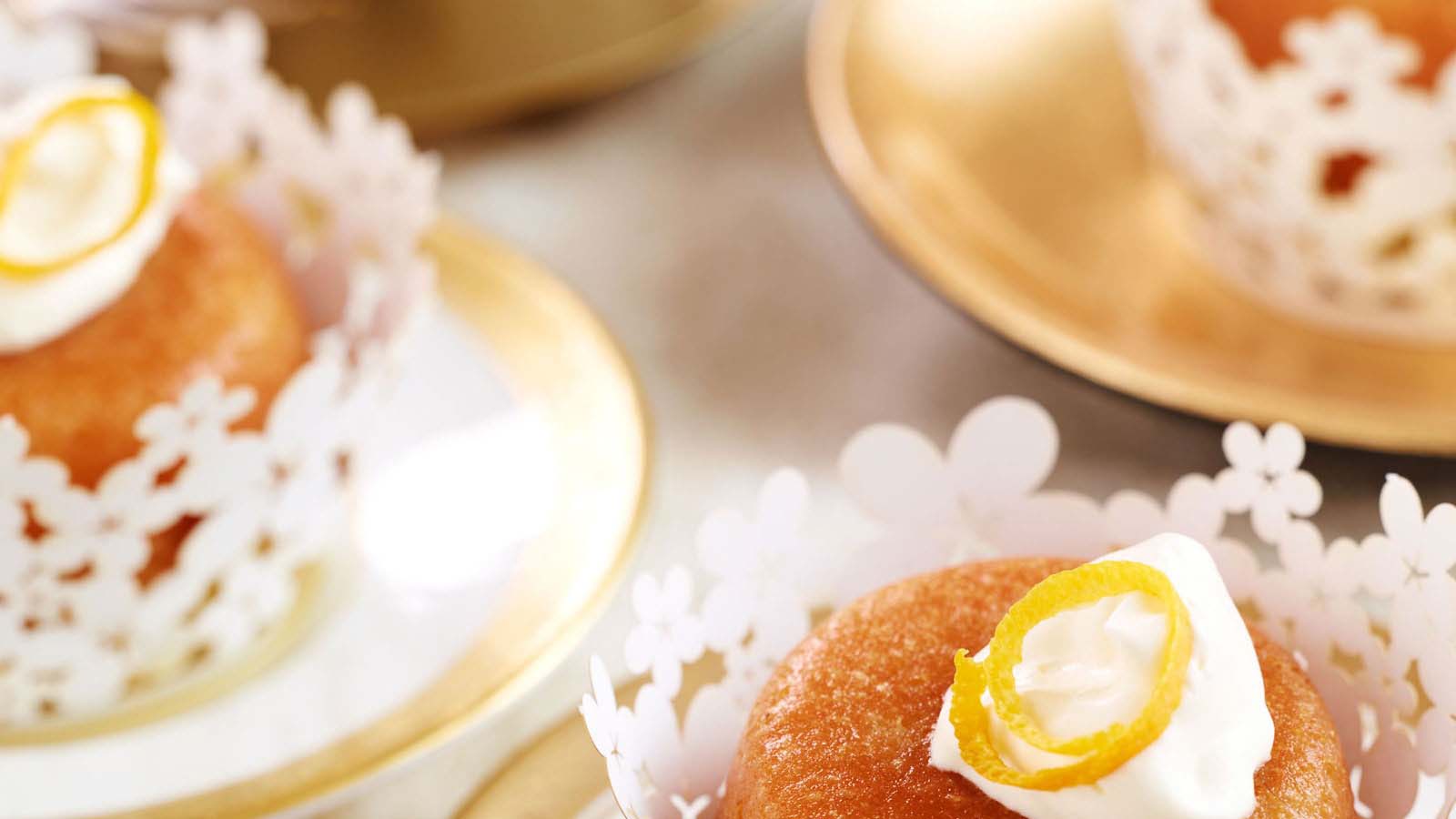 Spongy rum baba yeast cakes soaked in sweet rum syrup and topped with cream.