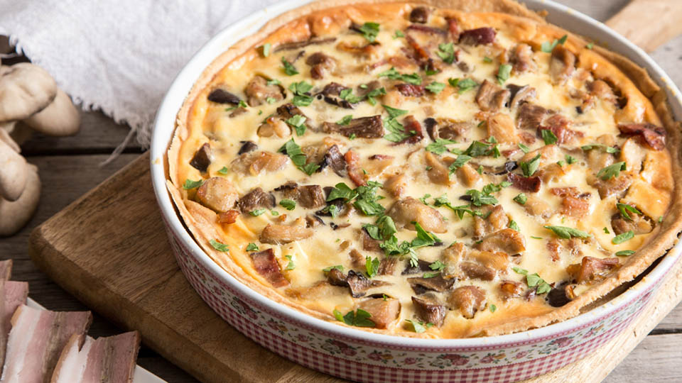 A large, rustic savoury tart or quiche loaded with roasted vegetables and cheese filling.
