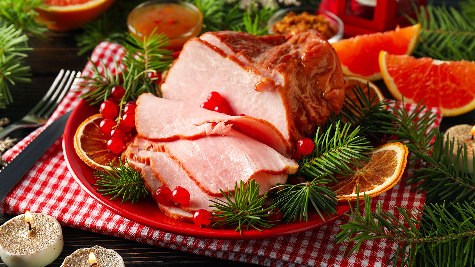 A premium wood-smoked Christmas ham holiday centerpiece roast on a carving board.