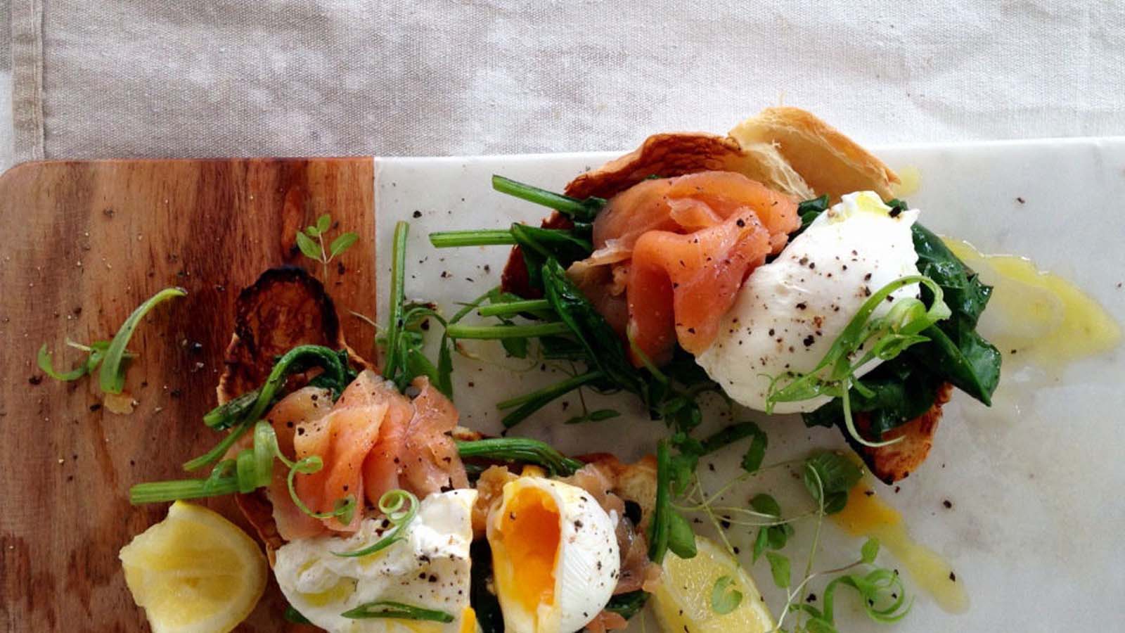 A luxury breakfast croissant stuffed with smoked salmon ribbons, cream cheese, and a poached egg.
