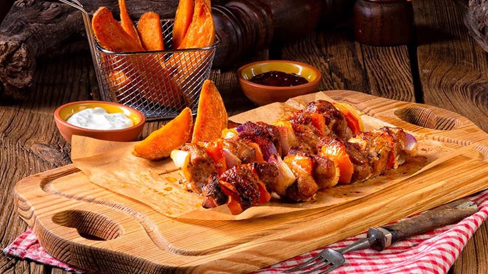 Traditional South African spiced lamb kebabs sosaties grilled over hot braai barbecue coals.