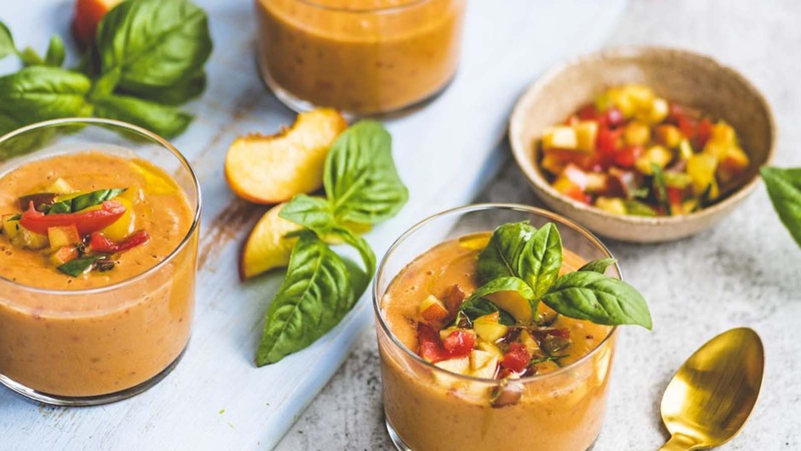 A classic bright red cold Spanish gazpacho soup garnished with fresh herbs.