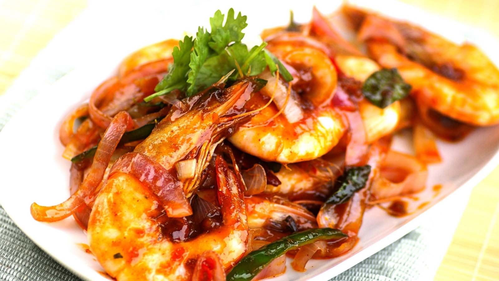 A plate of sizzling pan-seared spicy prawns seasoned with chili and garlic butter sauce.