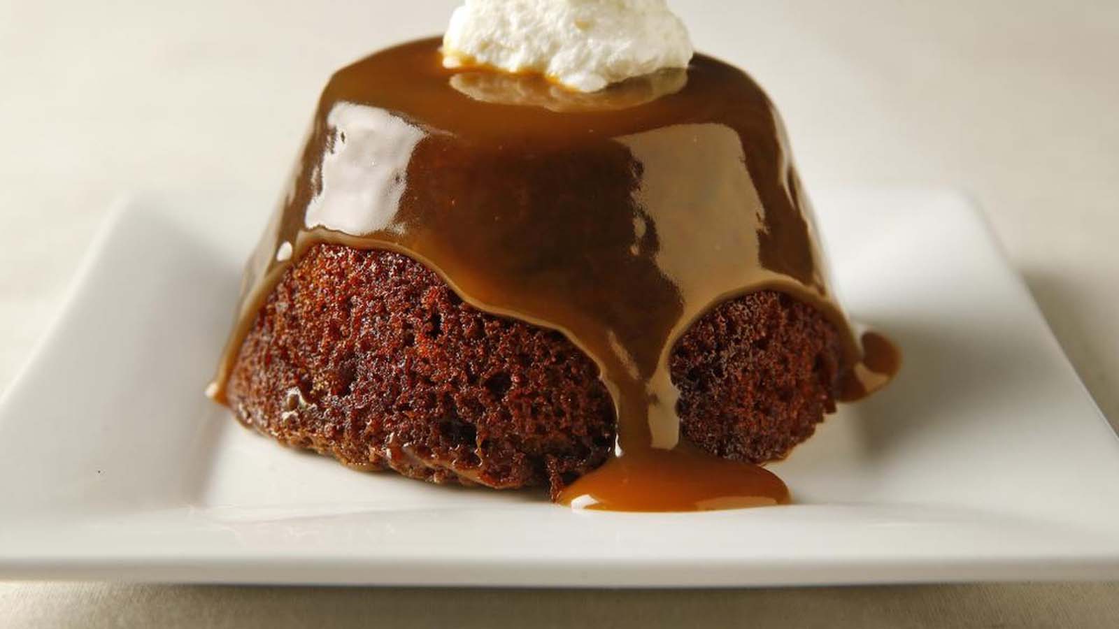 A rich, dark sticky toffee pudding square drenched in warm butterscotch sauce.