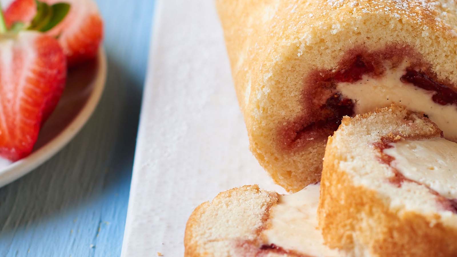 A classic golden sponge swiss roll cake rolled tightly with sweet strawberry jam filling.