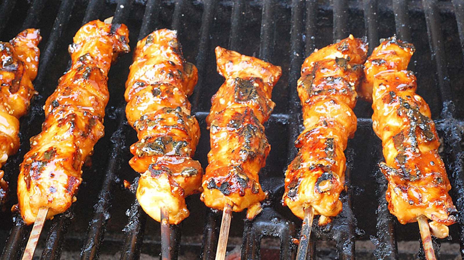 Grilled tandoori chicken kebabs with charred peppers and onions on wooden skewers.