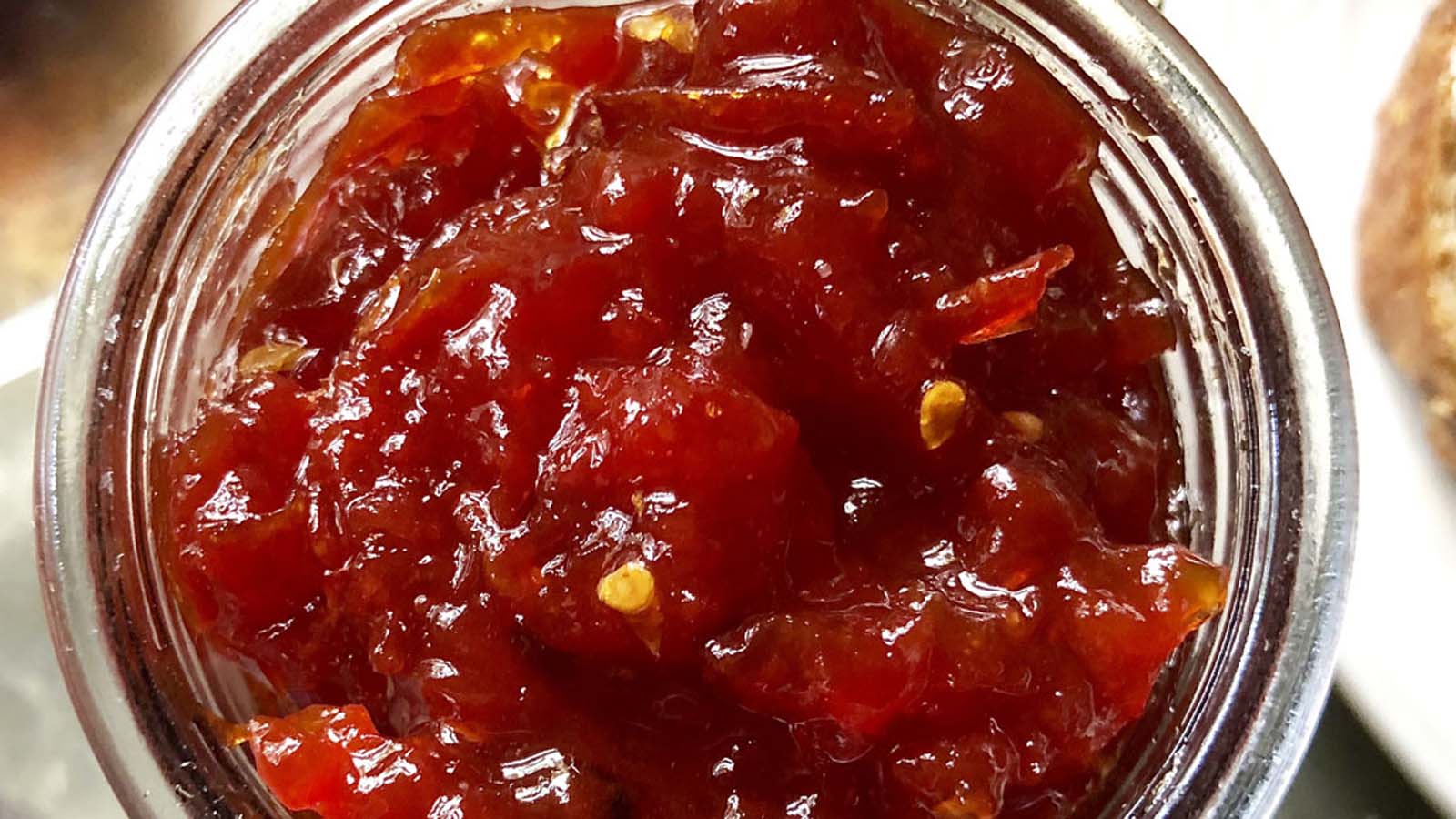 Vibrant red sweet tomato and chili jam relish in a clear serving container.