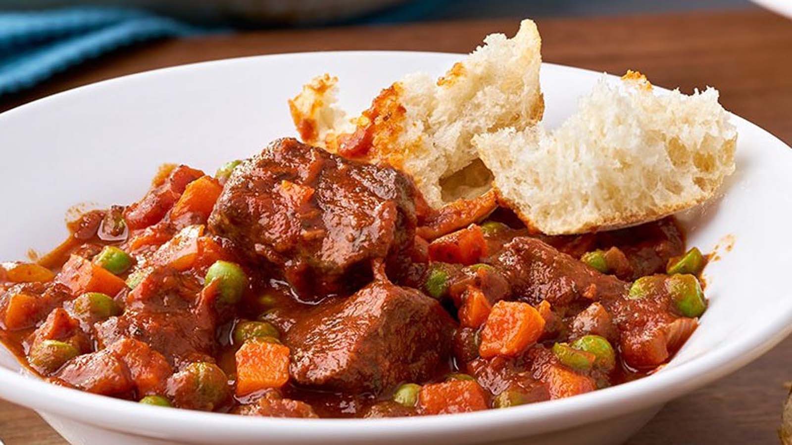 A rich and thick homemade tomato stew simmering with fresh herbs in a pot.
