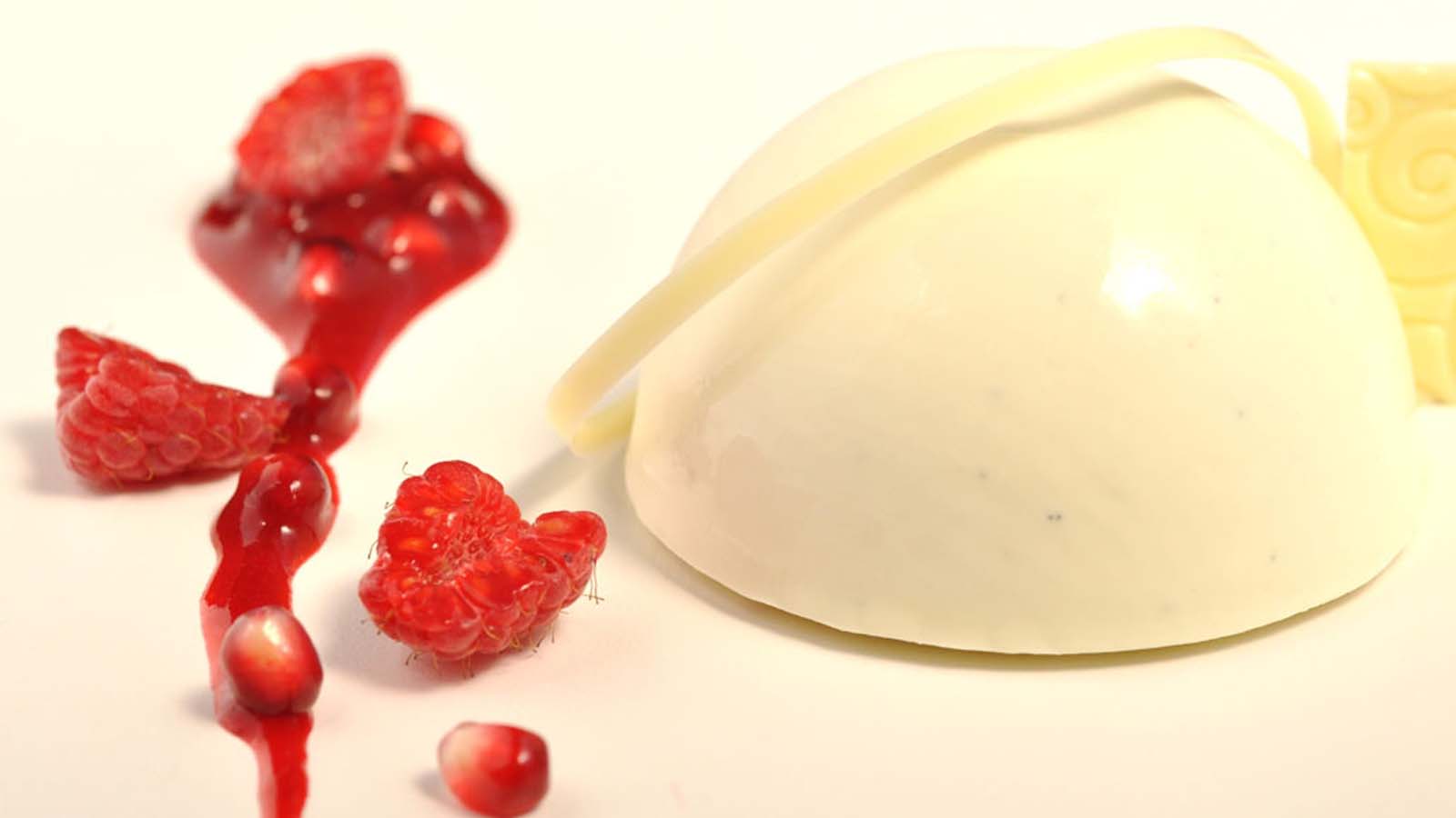 A molded vanilla Bavarian cream dessert wobbling gently next to fresh fruit berries.
