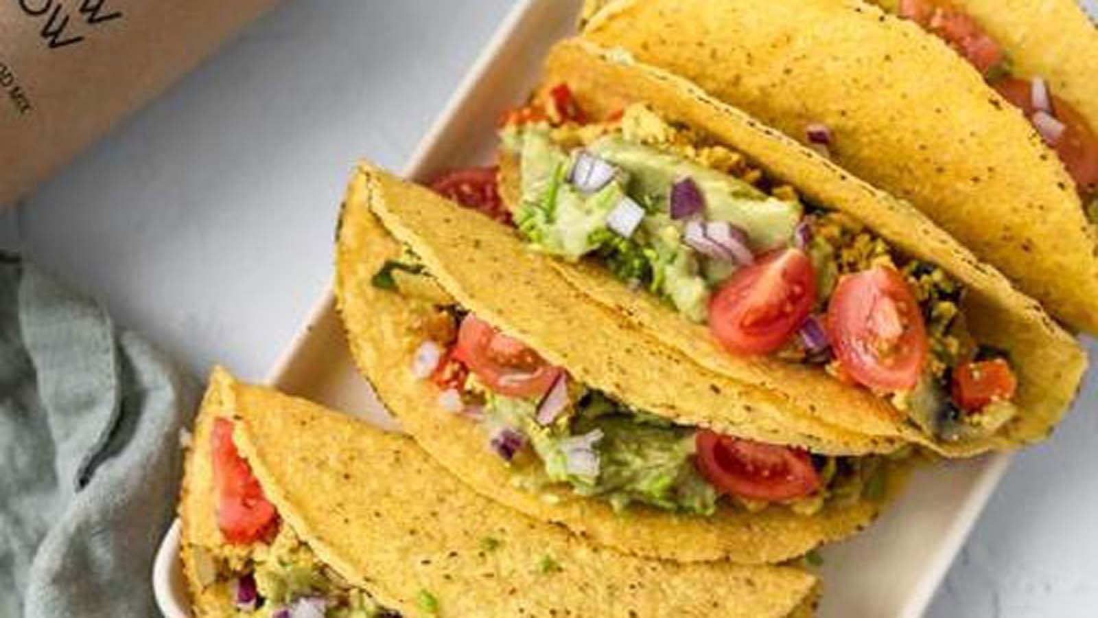 Two vibrant vegan breakfast tacos stuffed with avocado, black beans, and salsa mix.