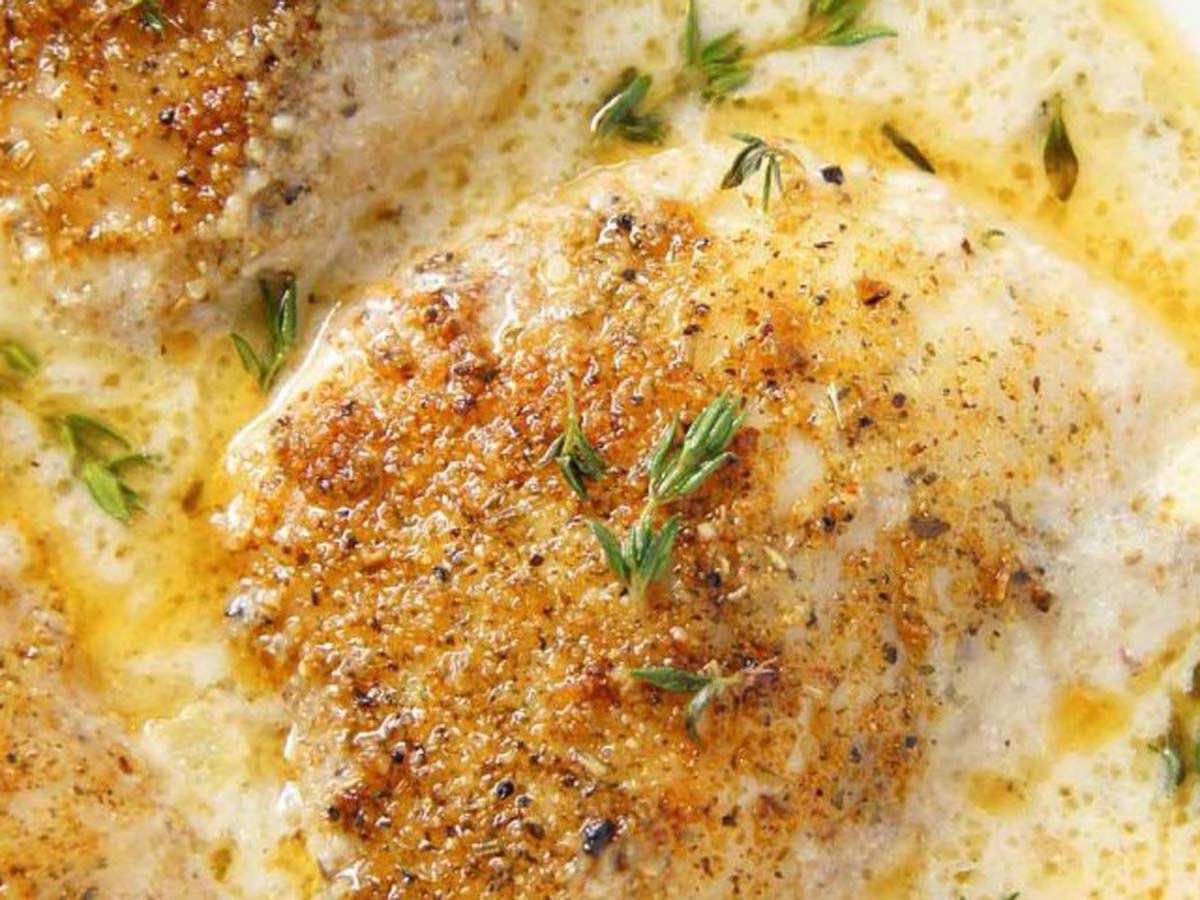 Rich garlic and thyme sauce simmering in a saucepan, perfect for a braai or steak barbecue.