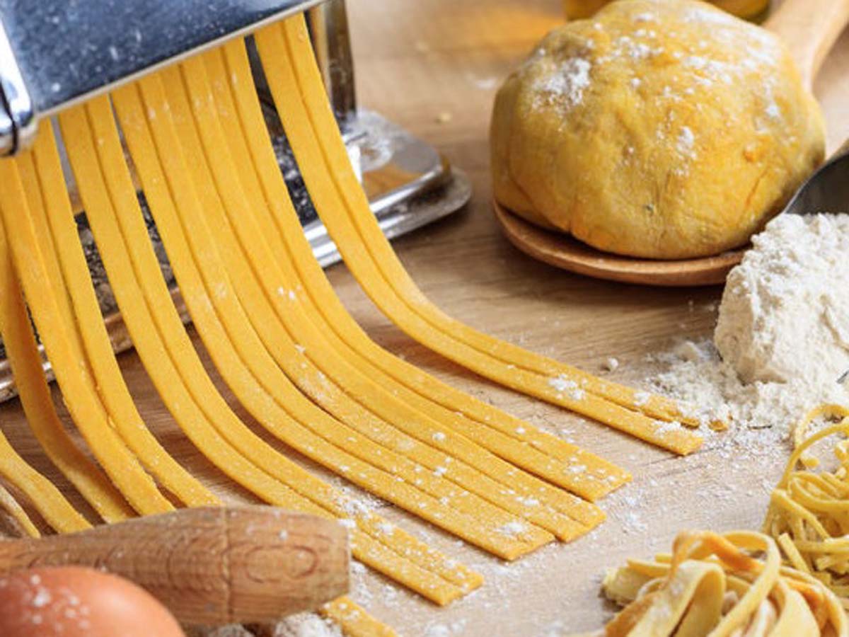 Freshly rolled out smooth yellow basic pasta dough on a floured workbench.