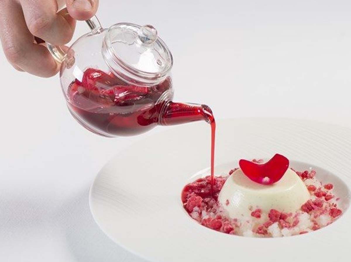 Festive creamy raspberry Christmas panna cotta topped with fresh red berries and syrup.
