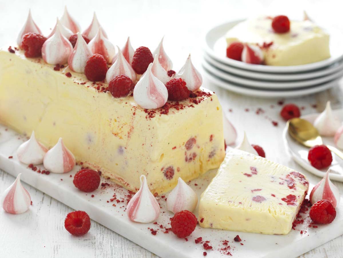 An elegant white chocolate and nougat semifreddo frozen dessert sliced on a platter.