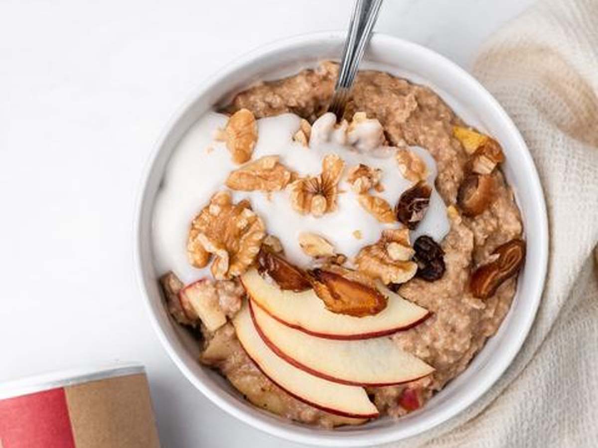 A warm, wholesome breakfast bowl of apple cinnamon oatmeal porridge topped with fruit.