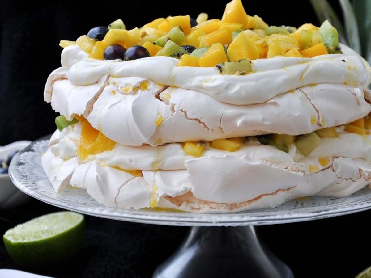 A giant, beautiful Australian pavlova meringue cake loaded with cream and summer berries.