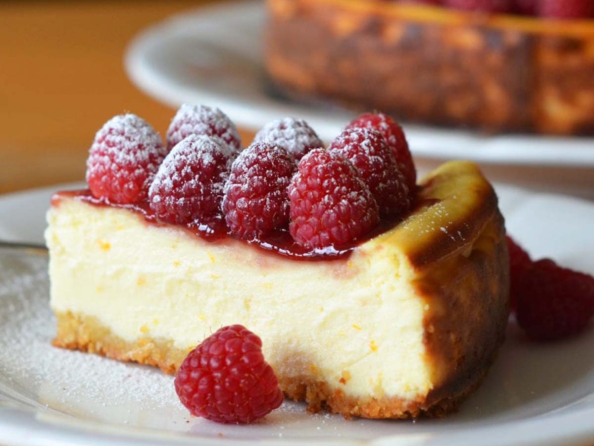 A slice of creamy baked cheesecake with a golden crumb crust on a dessert plate.