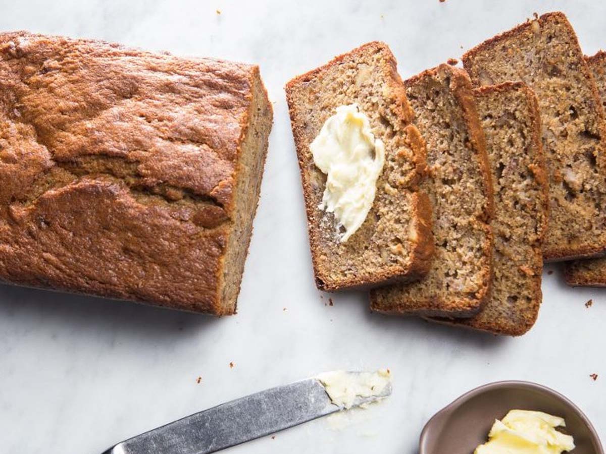 Moist homemade banana loaf sliced neatly on a cooling rack.