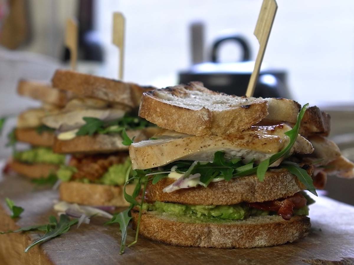 A layered BBQ chicken club sandwich sliced diagonally into neat triangles.