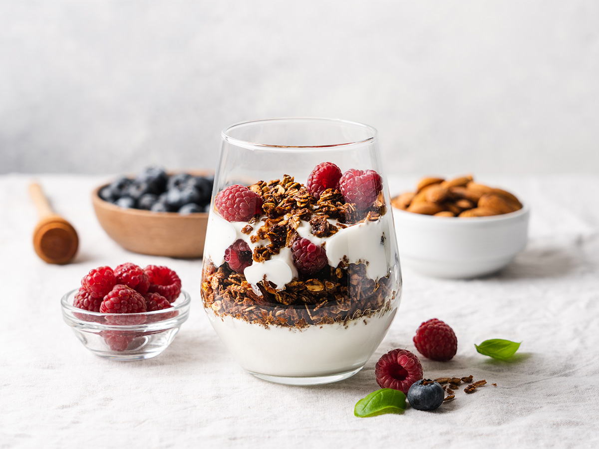 A healthy breakfast glass parfait layered with granola, yogurt, and fresh mixed fruits.