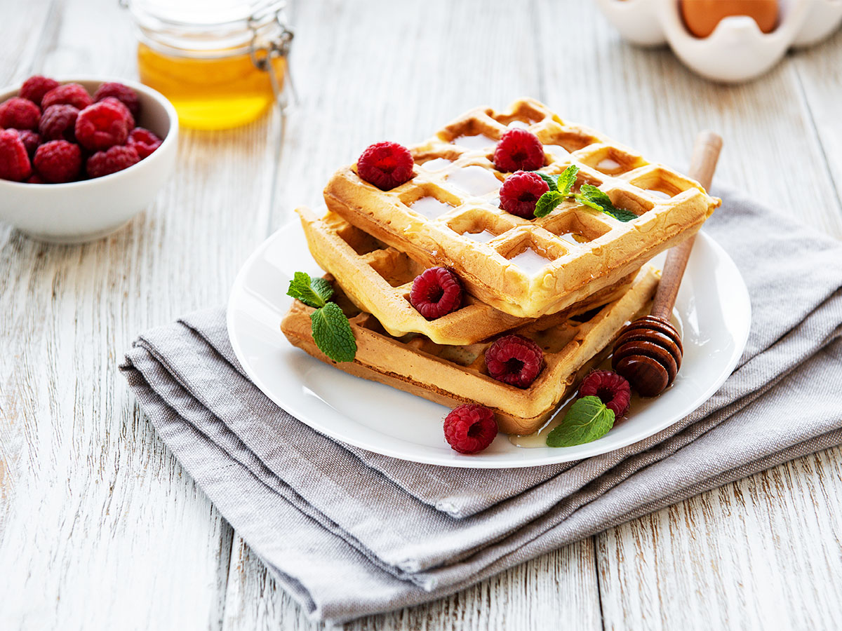 A crispy golden breakfast waffle topped with a vibrant assortment of fresh mixed fruits.