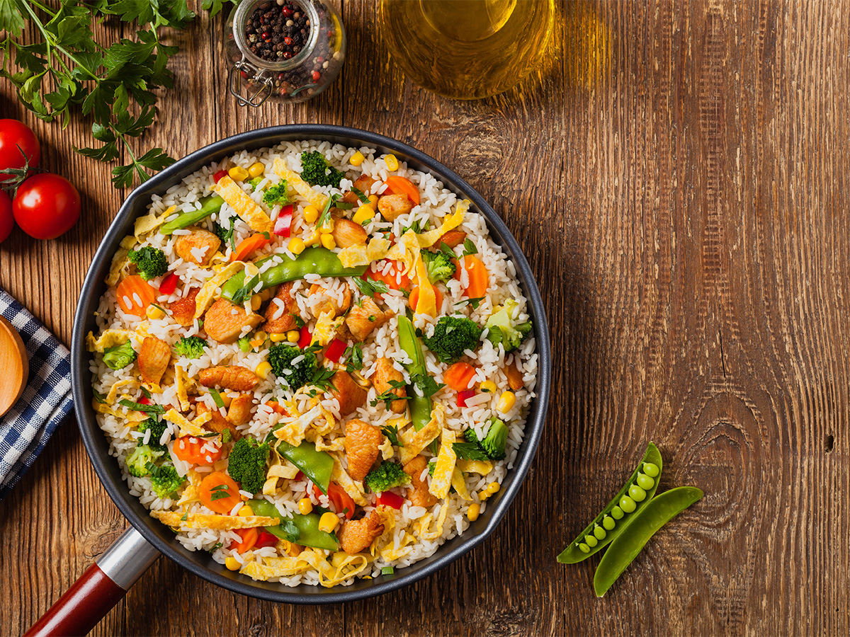 A hot wok filled with savoury chicken egg fried rice tossed with green peas.